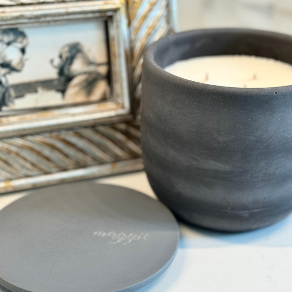 Custom concrete candle in charcoal gray. An example of the engraved lid shows the dog naemorial came, "Magge" in an elegant script font. Each concrete candle is 5.5" in diameter and 3.5" deep with three wicks to burn evenly. Choose a fragrance sucj as Rolling in the grass, Big Stick and also Unscented. Makes the perfect custom pet memorial gift.