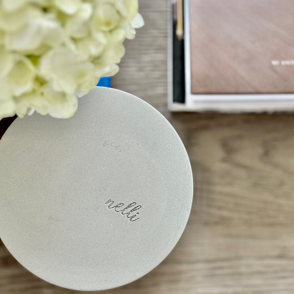 Custom concrete candle in charcoal gray. An example of the engraved lid shows the dog naemorial came, "Magge" in an elegant script font. Each concrete candle is 5.5" in diameter and 3.5" deep with three wicks to burn evenly. Choose a fragrance sucj as Rolling in the grass, Big Stick and also Unscented.  Makes the perfect custom pet memorial gift.